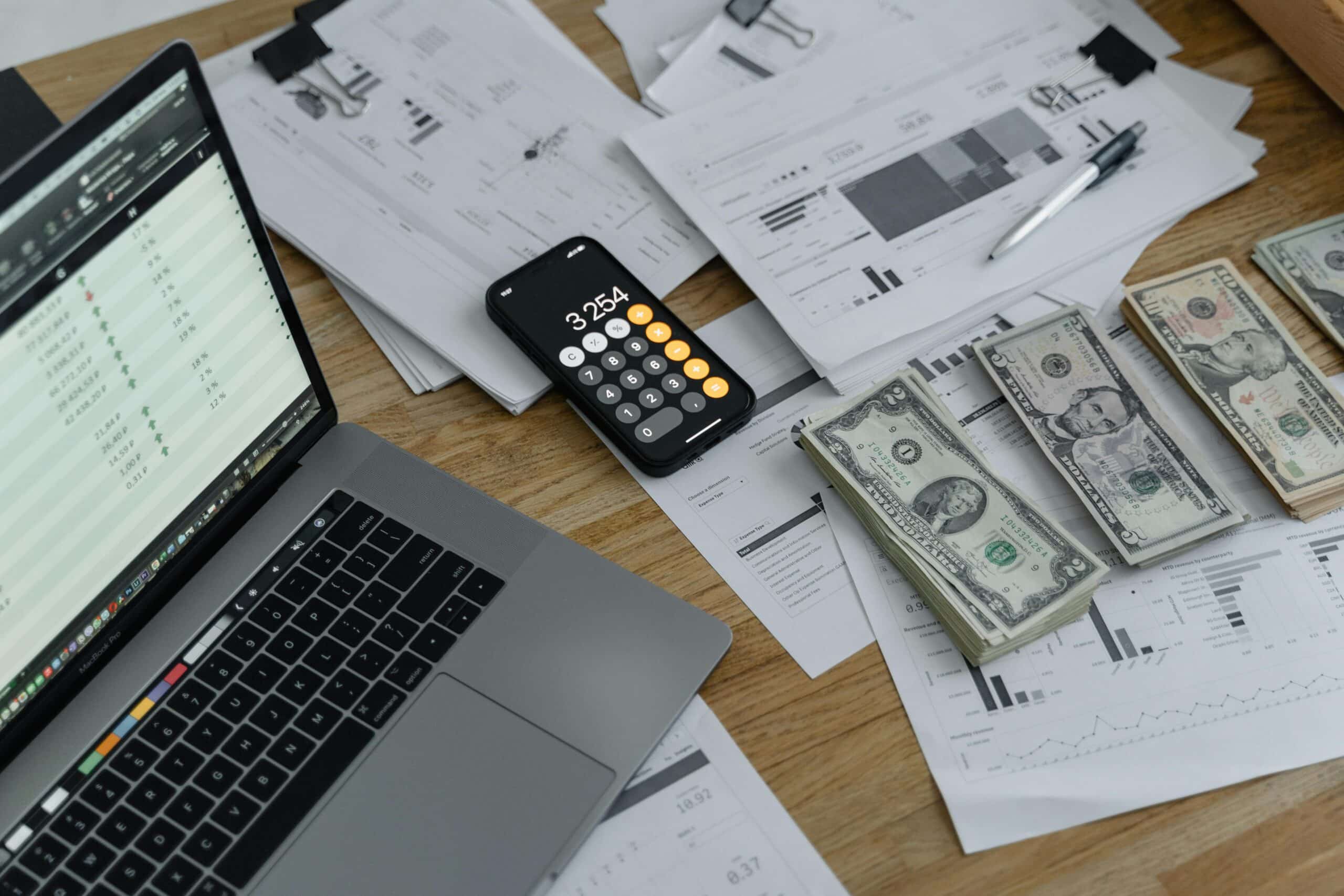 Ordinateur, calculatrice, billets et rapports financiers sur un bureau